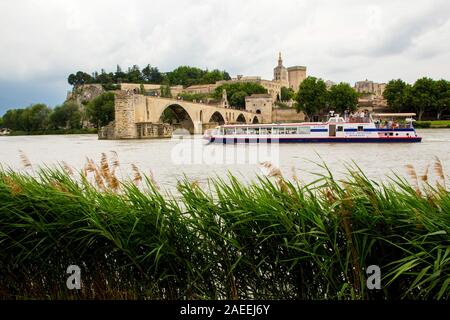 A boat passes the Pont d'Avignon spanning part way across the Rhone River in Avignon France Stock Photo