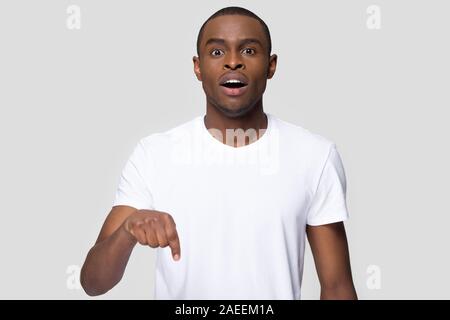 Surprised African American man with open mouth pointing finger down Stock Photo