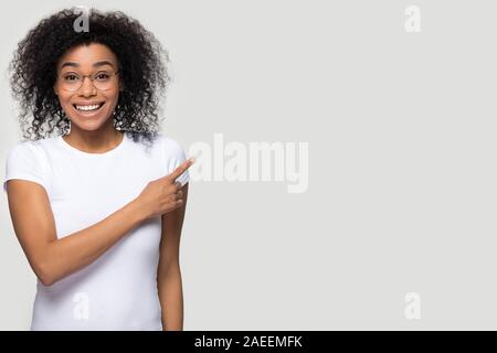 Smiling African American woman in glasses pointing finger at copy space Stock Photo
