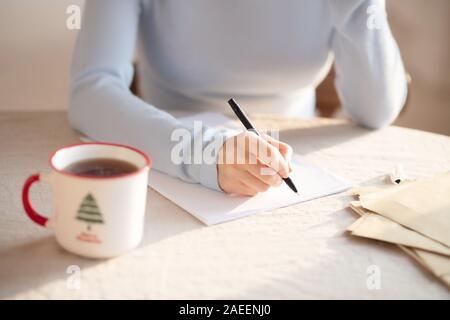 Woman in grey sweater sitting at the table and making notes Stock Photo