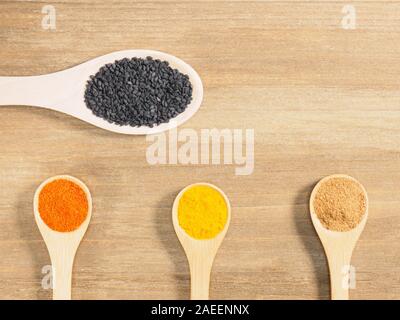 Turmeric, masala, chili pepper, black cumin in spoon on brown wooden background. Indian cuisine, ayurveda, naturopathy, modern apothecary concept Stock Photo