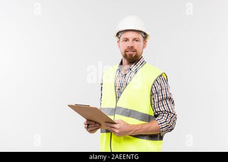 Cheerful engineer with clipboard looking at you while standing in isolation Stock Photo