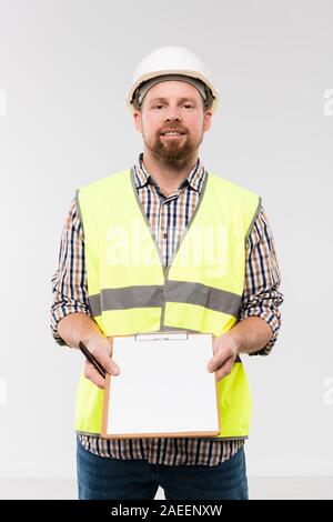 Cheerful young foreman showing clipboard with notes on paper in isolation Stock Photo