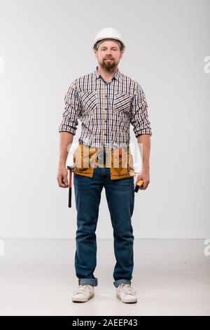 Young technician with toolbelt on his waist standing in front of camera Stock Photo