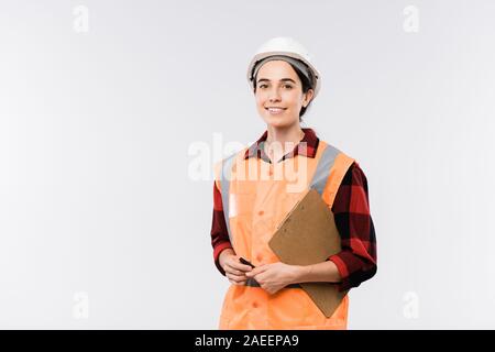 Successful young female engineer in protective helmet and orange jacket Stock Photo