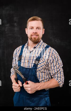 Young technician or repairman in shirt and overalls using handtool in isolation Stock Photo