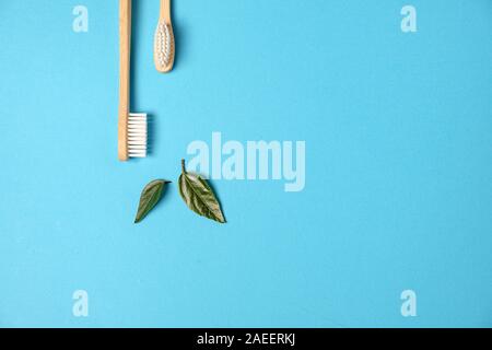 Zero waste. Two wooden bamboo eco friendly toothbrushes and green leaf on blue background. Dental care and Eco friendly and reuse concept. Flat lay, t Stock Photo