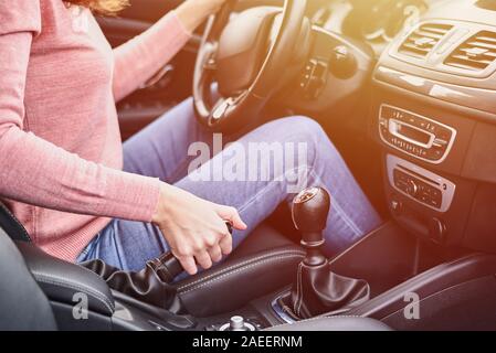 Female hand pulling handbrake in the car. Woman driving car Stock Photo