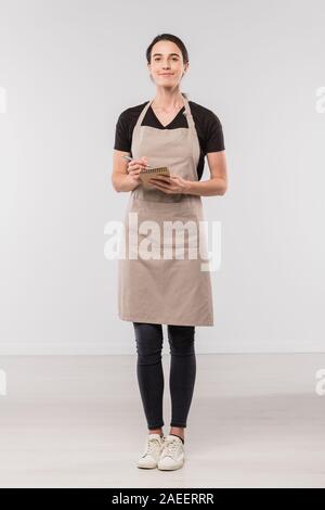 Pretty brunette waitress in workwear making notes in small notepad Stock Photo