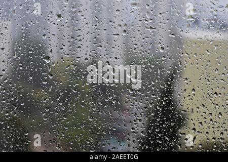 Rain drops on window glass background at rainy day blurred outside sky cloud blue texture - Image Stock Photo