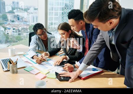 Serious business team gathered together at office table to discuss annual financial report Stock Photo