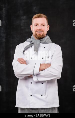 Happy young male chef with his arms crossed by chest looking at you Stock Photo