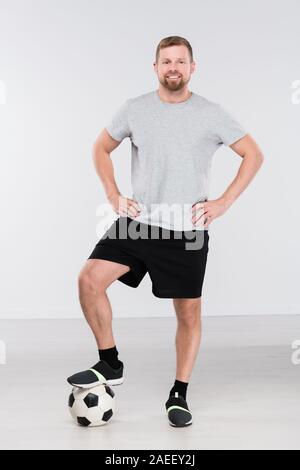 Young professional soccer player with foot on ball standing in front of camera Stock Photo