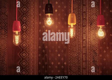 Decorative incandescent bulbs glow on the background of a wall with an ornament. Original interior decoration Stock Photo