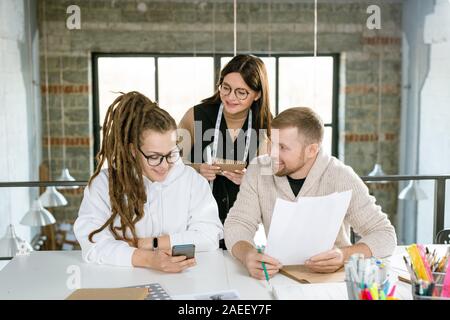 Group of young successful designers of clothes discussing new creative ideas Stock Photo