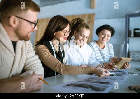 Young creative designers discussing fashion sketches while working in studio Stock Photo
