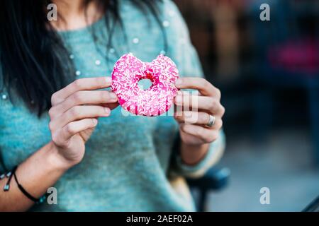 Woman is eating a delicious and colored donut. Stock Photo