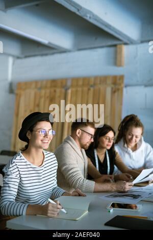 Happy young female fashion designer making notes or sketches in copybook Stock Photo