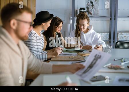 Group of happy young women discussing creative ideas while working in studio Stock Photo