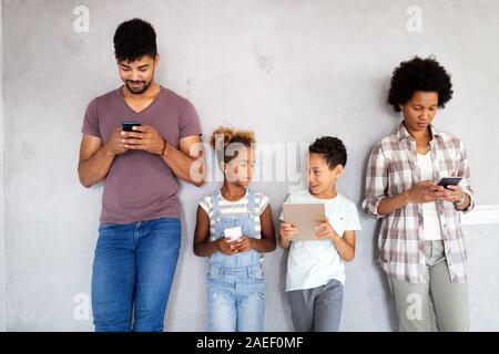 Happy african family using digital devices, tablet, smartphone. Technology concept Stock Photo
