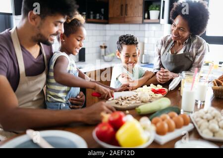 Happy african american family preparing healthy food together in kitchen Stock Photo