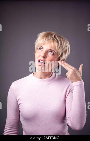 Woman with short blond hair showing gun gesture. People and emotions concept Stock Photo