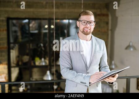 Young successful elegant fashion designer with magazine working in studio Stock Photo