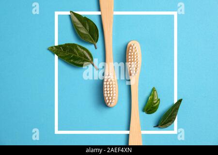 Zero waste. Two wooden bamboo eco friendly toothbrushes, white frame and green leaf on blue background. Dental care and Eco friendly and reuse concept Stock Photo