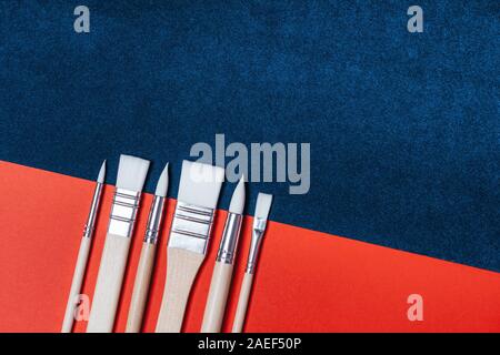 Art brushes of different shapes and sizes on a two-color red-blue background Stock Photo