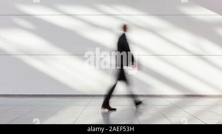 Anonymous blurred businessman goes gear in the office or on a trade fair Stock Photo