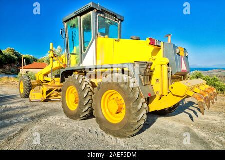 Yellow bulldozer on wheels laying asphalt concrete. Building work on a road. Work in progress, industrial machine. Stock Photo