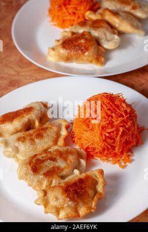 Polish dumplings with carrot salad. Dumplings fried in gold. Polish delicacies. Europe Poland. Stock Photo