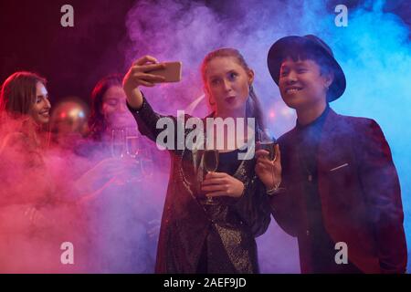 Portrait of young couple taking selfie photo on dnce floor while enjoying party in night club Stock Photo