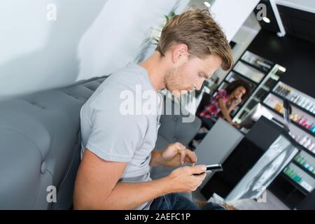 man using smartphone while waiting for hairdressers appointment Stock Photo