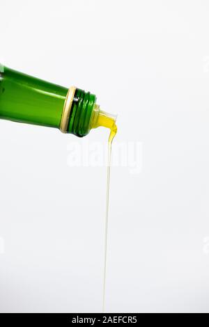 Oil pouring out of a glass bottle, isolated background. Fine vegetable oil, close-up view Stock Photo