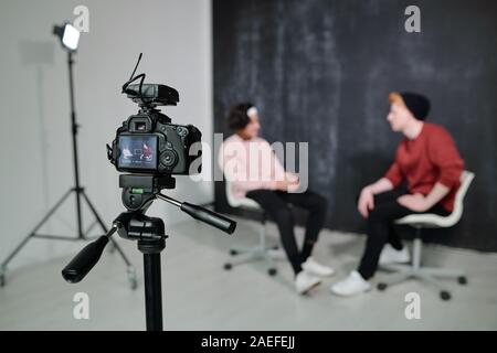Screen of digital video camera with two vloggers having conversation in studio Stock Photo