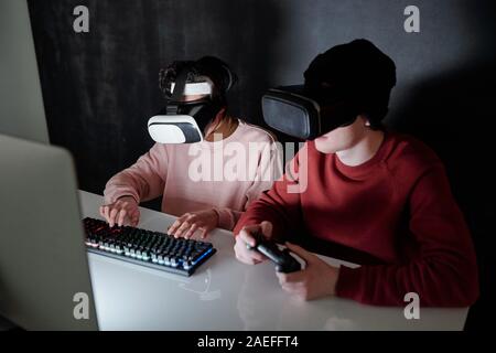 Two contemporary teenagers in vr headsets playing computer games Stock Photo