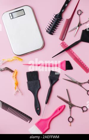 Hairdresser tools: scales, brushes, scissors, combs and clips over pink Stock Photo