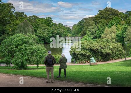 Mature couple park, rear view of a mature couple pausing to look at the lake in Ørstedsparken, a public park in the center of Copenhagen, Denmark. Stock Photo