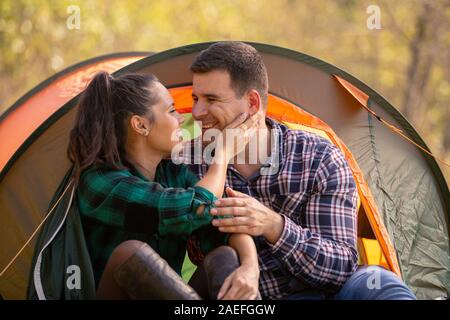 Loving couple smiling while looking at each other in front of the tent. Romantic atmoshere Stock Photo
