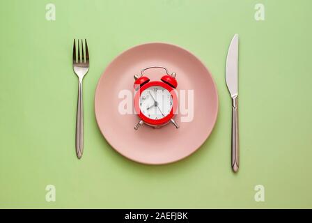 Red alarm clock on a clean pink plate Stock Photo