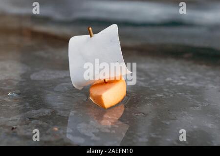 A small foam boat floats on a spring stream and the glint of the sun play on it. Close-up. Stock Photo
