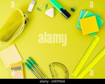 Top view of modern bright green office desktop with school supplies on table, empty space for text. Back to school concept. Stock Photo
