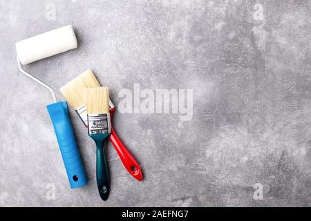 Paint roller and two brushes on gray background. Top view with copy space.