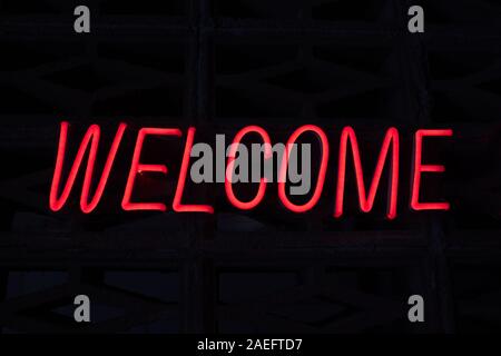 Red color neon glowing sign text welcome on black background. Made from luminescent illuminated lamp Stock Photo
