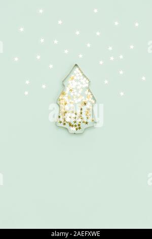 Christmas tree made with mold for the cookies and silver sparkling stars on blue background. Flat lay. Holidays and winter concept Stock Photo