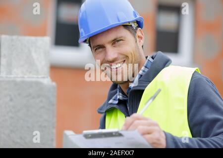 handsome happy workman writing on clipboard Stock Photo