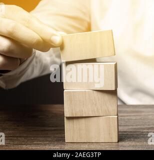 Businessman puts wooden blocks. Business management concept. Planning and strategy. Setting and achieving goals. Business stability. Road map. Stock Photo
