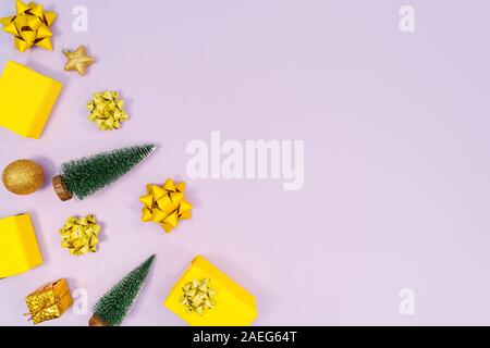 Christmas decoration. Gifts, yellow and golden decorations on purple background. Christmas, winter, new year concept. Flat lay, top view, copy space Stock Photo