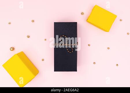 Christmas Gift box, black and yellow present box on pink background. Christmas, winter, new year concept. Flat lay, top view, copy space Stock Photo